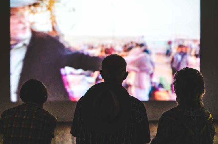 Three figures in front of a large projector screen