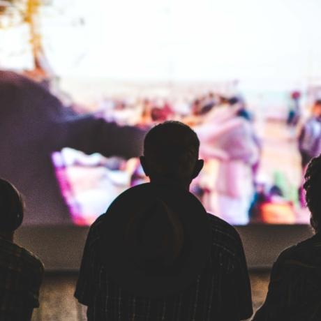 Three figures in front of a large projector screen